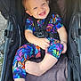 baby, child, stroller, smiling, happy, colorful_clothing, toddler, seatbelt, outdoor, daylight, cute, infant, person, sitting, foot, hand, face, blue_eyes, patterned_outfit, straps