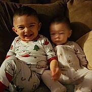 James is registered to the contest to win money with this photo: toddler, child, pajamas, smile, blurred, couch, indoor, happy, baby, sitting, blanket, face, home, cozy, young_child, clothing, furniture, cute, infant, portrait