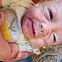 baby, infant, smile, face, hand, nasal_cannula, medical, clothing, arm, skin, cute, person, closeup, indoor, carpet, pattern, holding, healthcare, newborn, expression