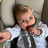 Ellie a rejoint le concours — aidez-le/la à gagner de superbes lots ! baby, infant, car_seat, safety_harness, white_clothing, blue_prints, chewing, curious, rosy_cheeks, sparkling_eyes, hand, seat, child, cute, indoor, portrait, smiling, young_child, baby_girl, baby_boy