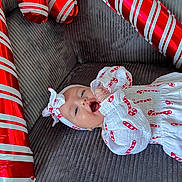 Ellie participe au concours pour gagner de l'argent avec cette photo : baby, infant, candy_cane, holiday, festive, balloon, red, white, striped, headband, couch, fabric, smile, celebration, child, clothing, happy, lying_down, indoor, person