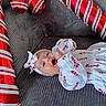 baby, infant, candy_cane, holiday, festive, balloon, red, white, striped, headband, couch, fabric, smile, celebration, child, clothing, happy, lying_down, indoor, person