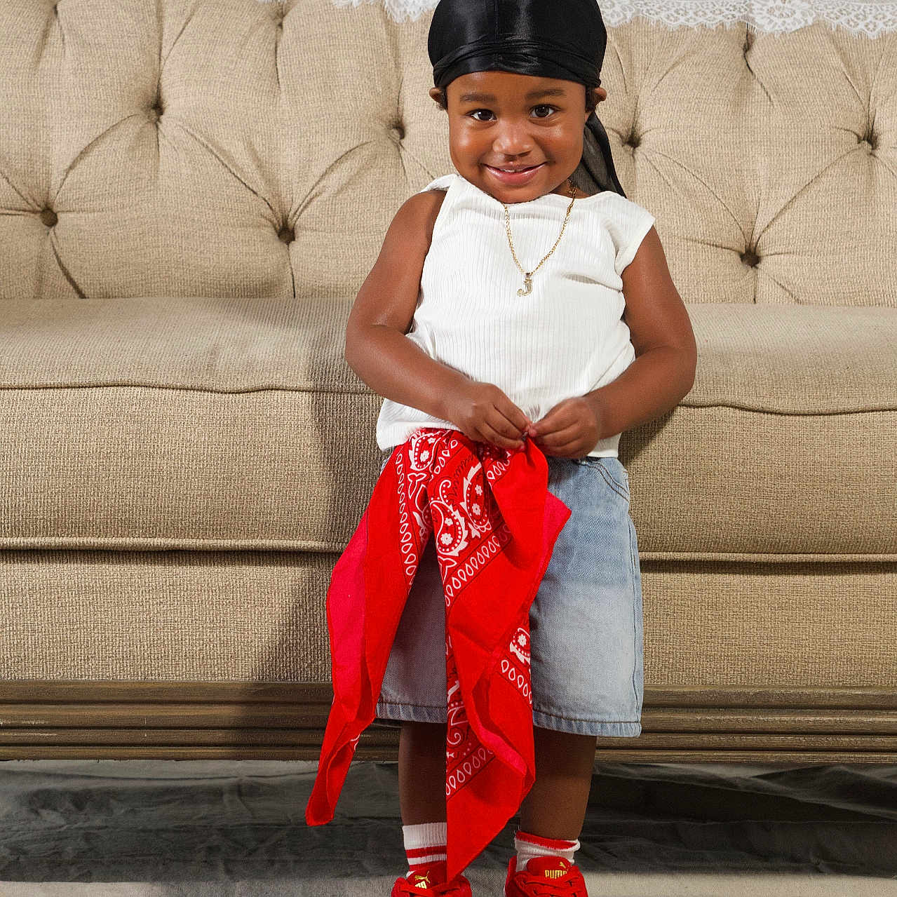 Jaicere joined the competition — help win amazing prizes! toddler, child, smiling, standing, red_sneakers, black_durag, white_top, denim_skirt, red_bandana, beige_couch, indoor, portrait, happy, cute, person, floor_covering, jewelry, necklace, fashion, casual