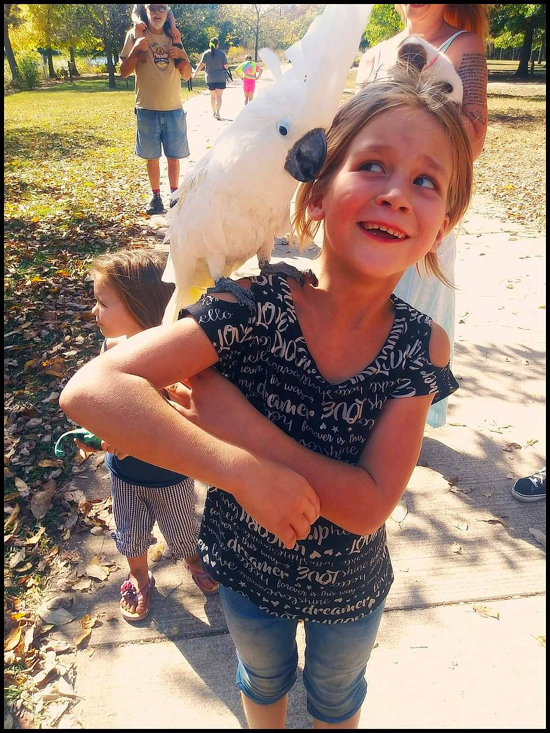 Nova is registered to the contest to win money with this photo: abdomen, child, fashion_accessory, fun, gesture, grass, happy, headwear, human_leg, jewellery, joy, leisure, pattern, person, recreation, sitting, smile, t_shirt, thigh, tree