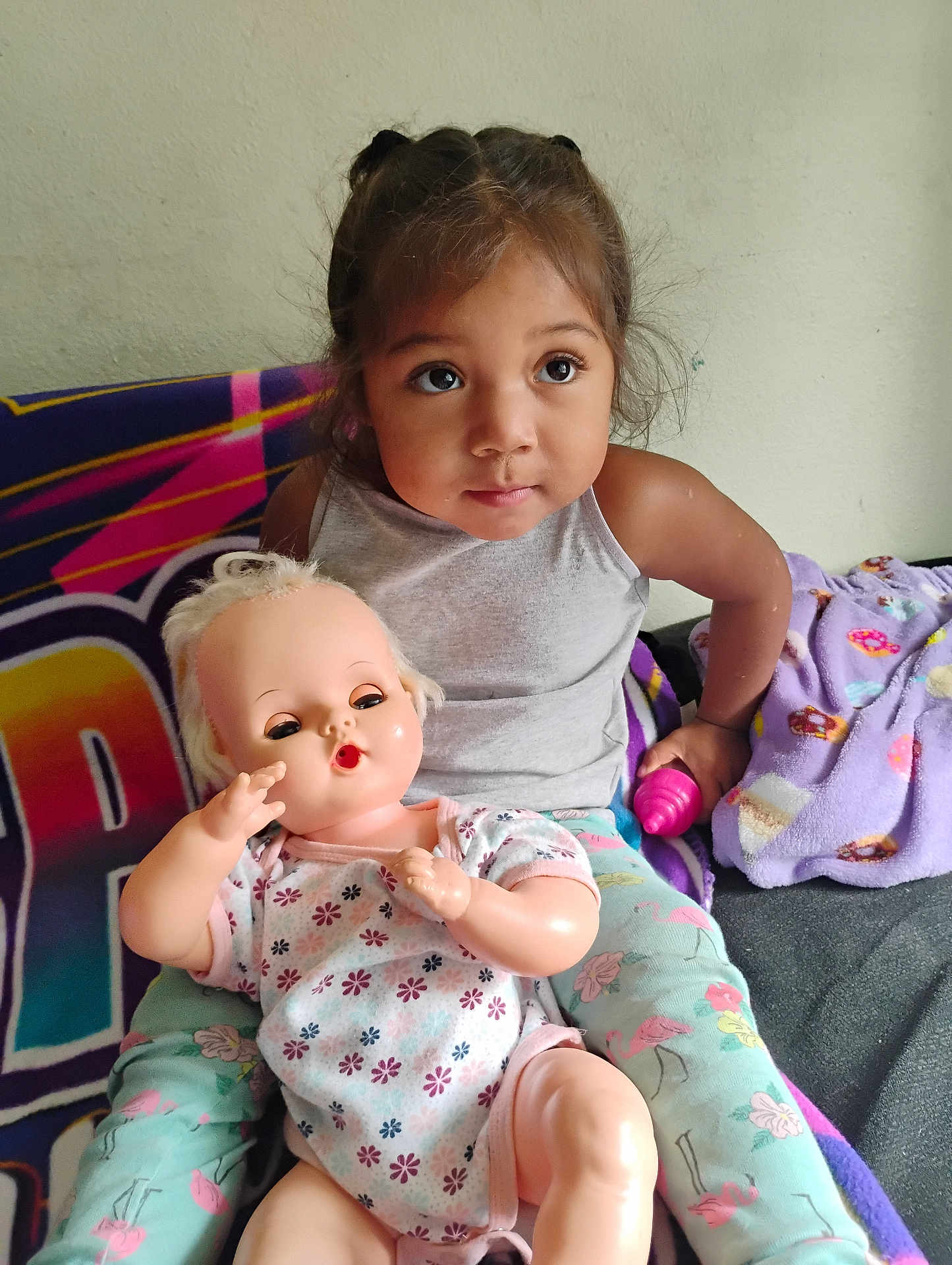 Heaven is registered to the contest to win money with this photo: child, doll, toy, blanket, colorful, indoor, girl, sitting, clothing, face, person, cute, playtime, expression, hair, pink, purple, pattern, relaxing, casual