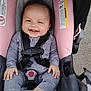 baby, car_seat, smiling, child, infant, onesie, gray_clothing, pink, seatbelt, happy, outdoor, straps, safety, cute, small_hands, foot, head, face, person, infant_clothing