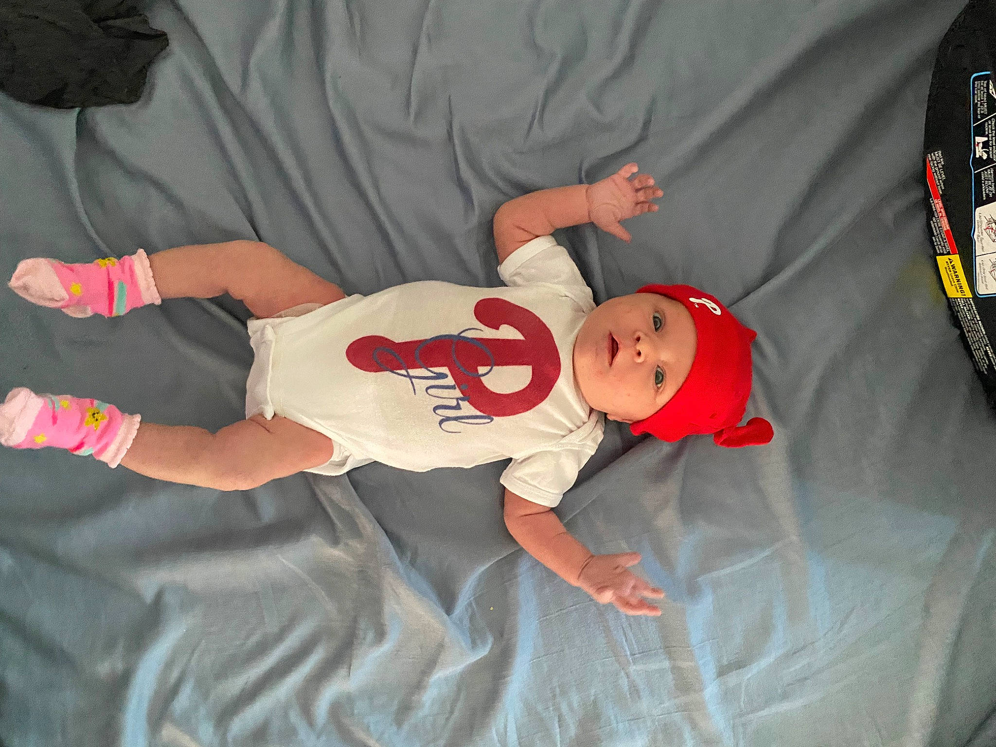 Freya is registered to the contest to win money with this photo: baby, baby_products, baby_toddler_clothing, carmine, child, comfort, elbow, finger, fun, hat, headwear, human_body, knee, linens, orange, person, room, sleeve, smile, t_shirt
