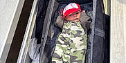 Dawson joined the competition — help win amazing prizes! baby, infant, camo_onesie, baseball_cap, carrier, bleachers, bench, plastic_cup, hand, outdoor, person, clothing, footwear, fabric, seat, sports, baby_gear, relaxing, casual, cute