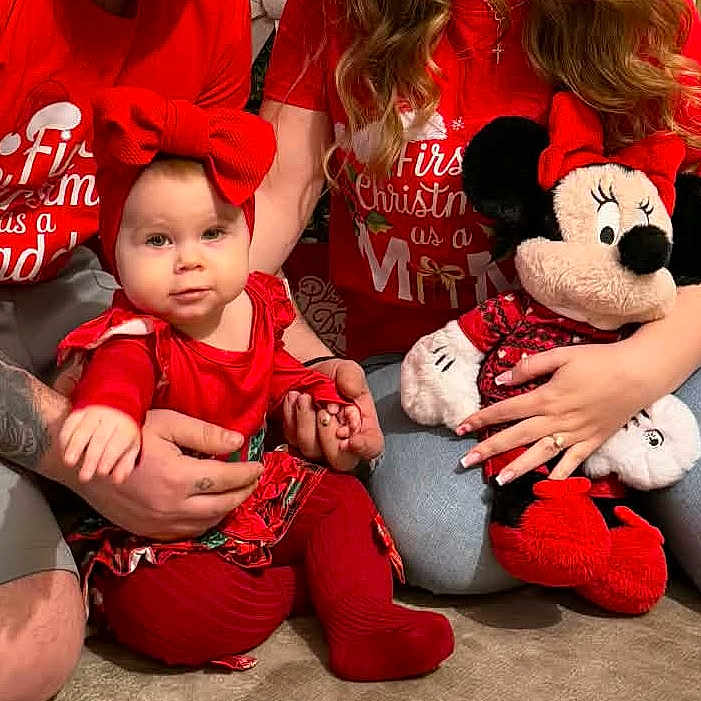 Selena participe au concours pour gagner de l'argent avec cette photo : adult, baby, bow, carpet, casual, child, christmas, family, holding, holiday, indoor, jeans, minnie_mouse, person, plush_toy, red_clothing, sitting, smiling, tattoo, tshirt