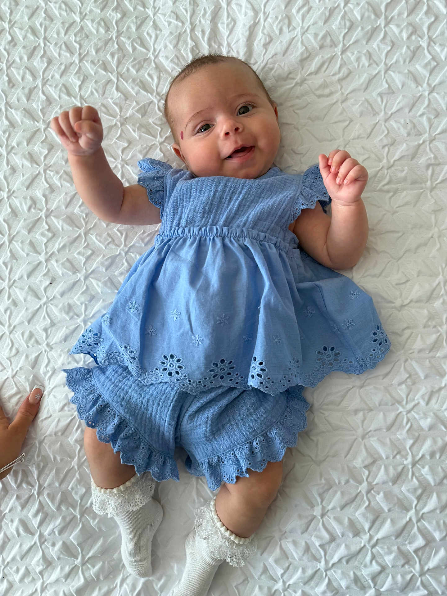 Blue joined the competition — help win amazing prizes! baby, infant, child, blue_dress, white_socks, smiling, lying_down, hand, blanket, textured_background, cute, happy, playful, frilly_clothing, portrait, closeup, skin, fingers, footwear, soft_lighting