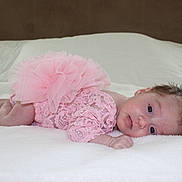 Zara is registered to the contest to win money with this photo: baby, infant, pink_dress, lace, blanket, bed, soft, cute, portrait, newborn, lying_down, blue_eyes, hair, indoors, child, resting, toddler, face, skin, sleepwear