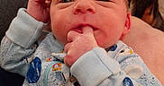 Elias is registered to the contest to win money with this photo: baby, babywear, closeup, clothing, curious, expression, face, fingers, hand, head, human, indoor, infant, newborn, onesie, person, portrait, skin, sleepwear, sucking
