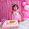 toddler, birthday, cake, pink, dress, flower_crown, balloons, streamers, celebration, party, child, happy, decorations, cake_topper, curious, indoors, standing, white, floor, festive