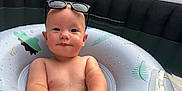 Oscar is registered to the contest to win money with this photo: baby, child, inflatable_ring, sunglasses, water, pool, outdoor, summer, cute, skin, droplets, float, backyard, plastic, fun, play, toy, person, relax, sun