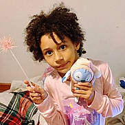 Connie joined the competition — help win amazing prizes! child, curly_hair, pajamas, stuffed_animal, plush_toy, wand, bedroom, blanket, bed, portrait, holding, smile, indoor, cozy, cute, play, person, toy_face, nightwear, hair