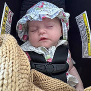 Feya is registered to the contest to win money with this photo: baby, blanket, car_seat, child, child_seat, closeup, cozy, cute, face, hat, headwear, indoor, infant, knit, peaceful, portrait, resting, safety_harness, sleeping, young_child