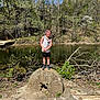 Brycen is registered to the contest to win money with this photo: child, boy, flower, stone, pond, trees, nature, outdoor, sunlight, spring, rocks, water, smile, casual_clothing, tank_top, shorts, sneakers, greenery, daytime, recreation