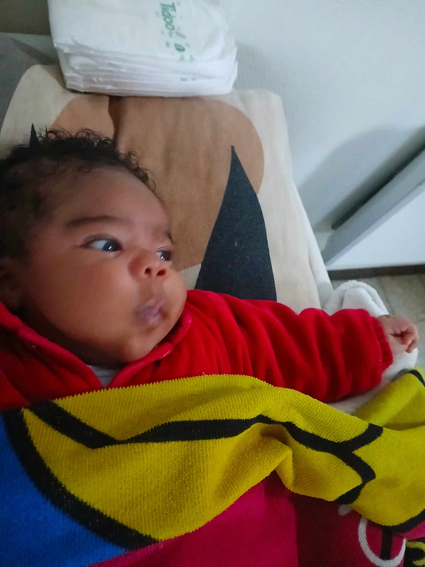 Aly participe au concours pour gagner de l'argent avec cette photo : baby, infant, child, blanket, red_clothing, curly_hair, diapers, cushion, indoor, person, face, portrait, looking_away, soft_toys, bed, sleeping_area, cozy, warm, head, toddler