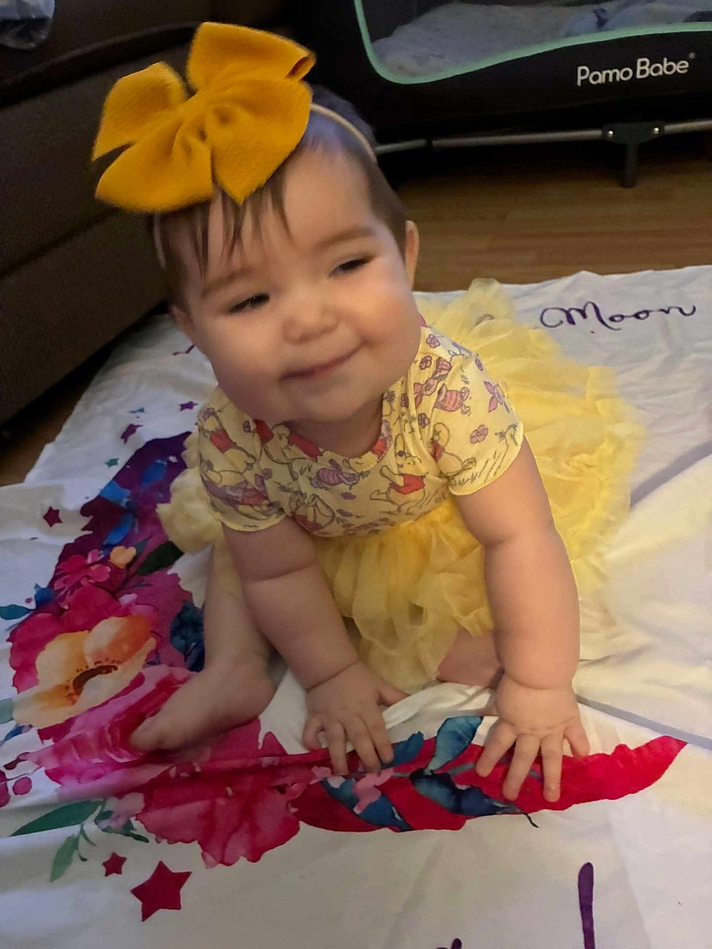 Sage joined the competition — help win amazing prizes! baby, child, yellow_bow, yellow_tutu, crawling, blanket, floral_pattern, indoor, playpen, floor, wooden_floor, cute, smiling, face, hands, feet, clothing, childhood, person, home