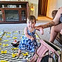 Sage is registered to the contest to win money with this photo: toddler, child, blue_dress, striped_blanket, yellow_bear_faces, pink_backpack, tattoo, adult_hand, living_room, carpet, figurines, decor, toy_penguin, stuffed_animal, person, furniture, doorway, wall_art, support, indoor