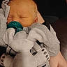 Skylar is registered to the contest to win money with this photo: baby, infant, sleeping, pacifier, stuffed_animal, elephant, toy, gray_clothing, onesie, bow, hand, adult_hand, portrait, indoor, cozy, nap, closed_eyes, face, child, photograph