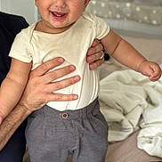 Owen joined the competition — help win amazing prizes! toddler, baby, child, smiling, standing, bed, clothing, pants, shirt, adult_hand, indoor, person, happy, cute, portrait, home, furniture, blanket, baby_gear, comfort