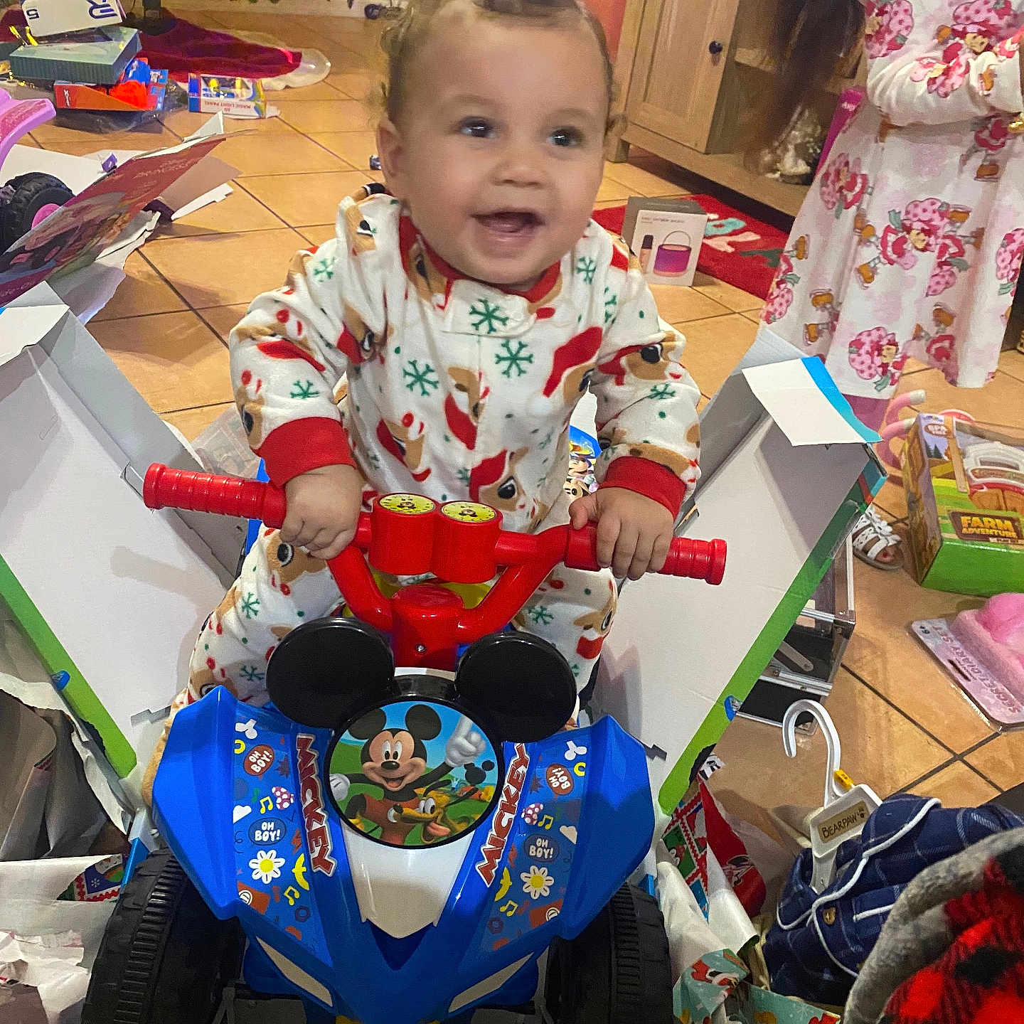 Jaden is registered to the contest to win money with this photo: cabinet, child, christmas_tree, family, festive, floor_tiles, gift_box, holiday, indoor, joyful, mickey_mouse, pajamas, person, playtime, smiling, toddler, toy, toy_vehicle, unwrapping, wrapping_paper