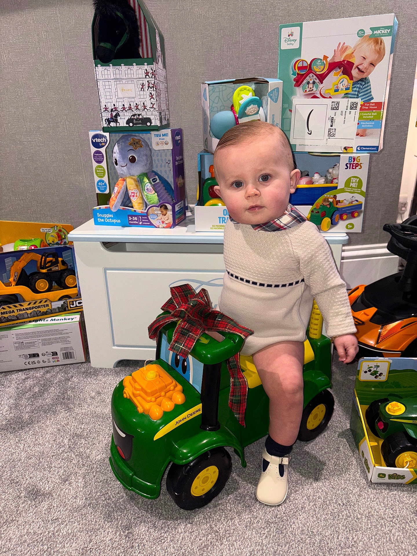 Henry joined the competition — help win amazing prizes! toddler, child, toy_tractor, john_deere, plaid_bow, indoor, carpet, toys, boxes, sweater, shoes, curious, baby, playroom, gift, vehicle, plastic_toy, floor, young_child, portrait