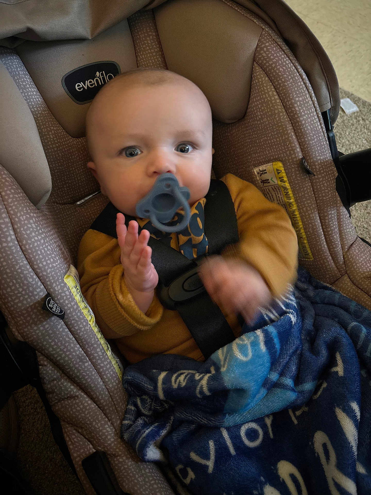 Taylor is registered to the contest to win money with this photo: baby, pacifier, car_seat, blanket, child, infant, seatbelt, blue, brown_clothing, indoor, car_seat_strap, soft_texture, toddler, person, cute, young_child, sitting, face, hands, closeup