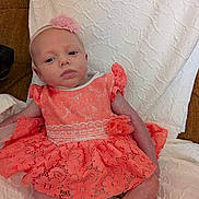 Ci'El is registered to the contest to win money with this photo: baby, infant, child, portrait, face, headband, flower, dress, coral, lace, sitting, lying_down, blanket, quilt, bed, indoors, brown_background, fashion, calm, photography