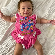 Lakelynn is registered to the contest to win money with this photo: baby, infant, smile, pink_dress, curly_hair, lying_down, white_blanket, polka_dots, child, cute, happy, toddler, face, arms_outstretched, clothing, portrait, indoor, skin, person, baby_girl