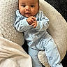 Legend is registered to the contest to win money with this photo: baby, infant, child, onesie, blue_clothing, blanket, cushion, soft_texture, indoor, portrait, cute, small_hands, face, head, lying_down, comfort, warm, cozy, looking_at_camera, expression