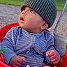 baby, child, swing, red_swing, hat, knit_hat, onesie, striped_clothing, hand, park, outdoor, grass, trees, curious, wide_eyes, seated, infant, playground, nature, daylight