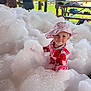 Kinsley is registered to the contest to win money with this photo: toddler, foam, bubbles, pink_hat, strawberry_outfit, child, outdoor, caution_tape, adult, grass, tree, mountain, bench, picnic_table, recreation, smile, play, sunhat, fun, family