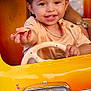 toddler, child, smiling, toy_car, steering_wheel, yellow, orange, happy, portrait, cute, outdoor, play, person, vehicle, closeup, baby, fun, joy, hand, face