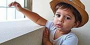 Luqmân participe au concours pour gagner de l'argent avec cette photo : toddler, child, hat, straw_hat, white_shirt, denim_jeans, indoor, window, natural_light, curious, leaning, portrait, young_child, casual_clothing, cute, expression, short_hair, person, baby, standing