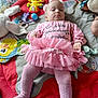 baby, pink_tutu, tights, headband, play_mat, toys, stuffed_animal, book, indoor, child, infant, clothing, laying_down, cute, serious_expression, colorful, soft_toys, floor, young_child, portrait