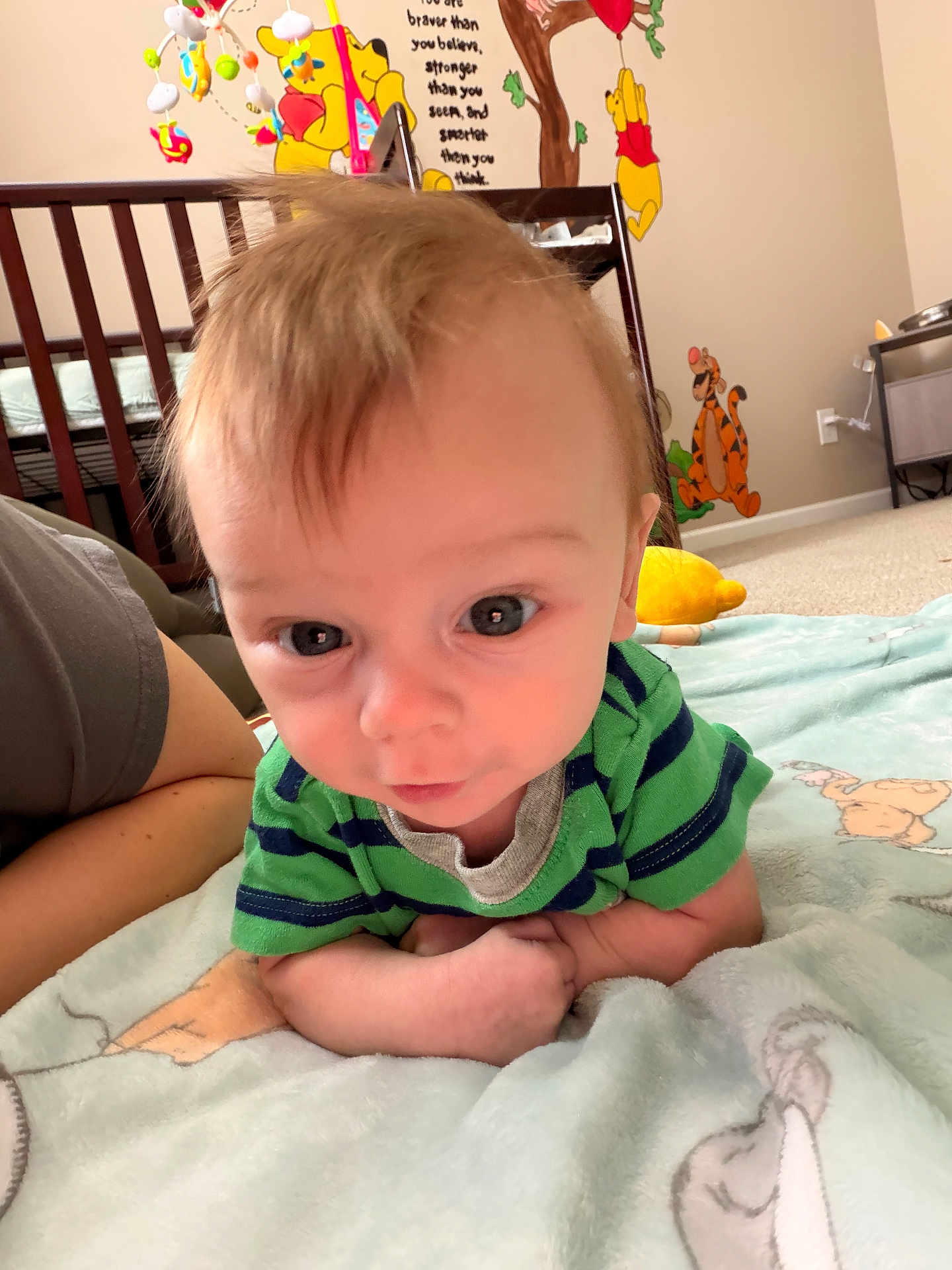 Oliver is registered to the contest to win money with this photo: baby, infant, child, nursery, crib, blanket, plush_toy, winnie_the_pooh, tigger, mobile, wall_decal, carpet, onesie, striped_shirt, closeup, portrait, eyes, hair, person, curious_expression