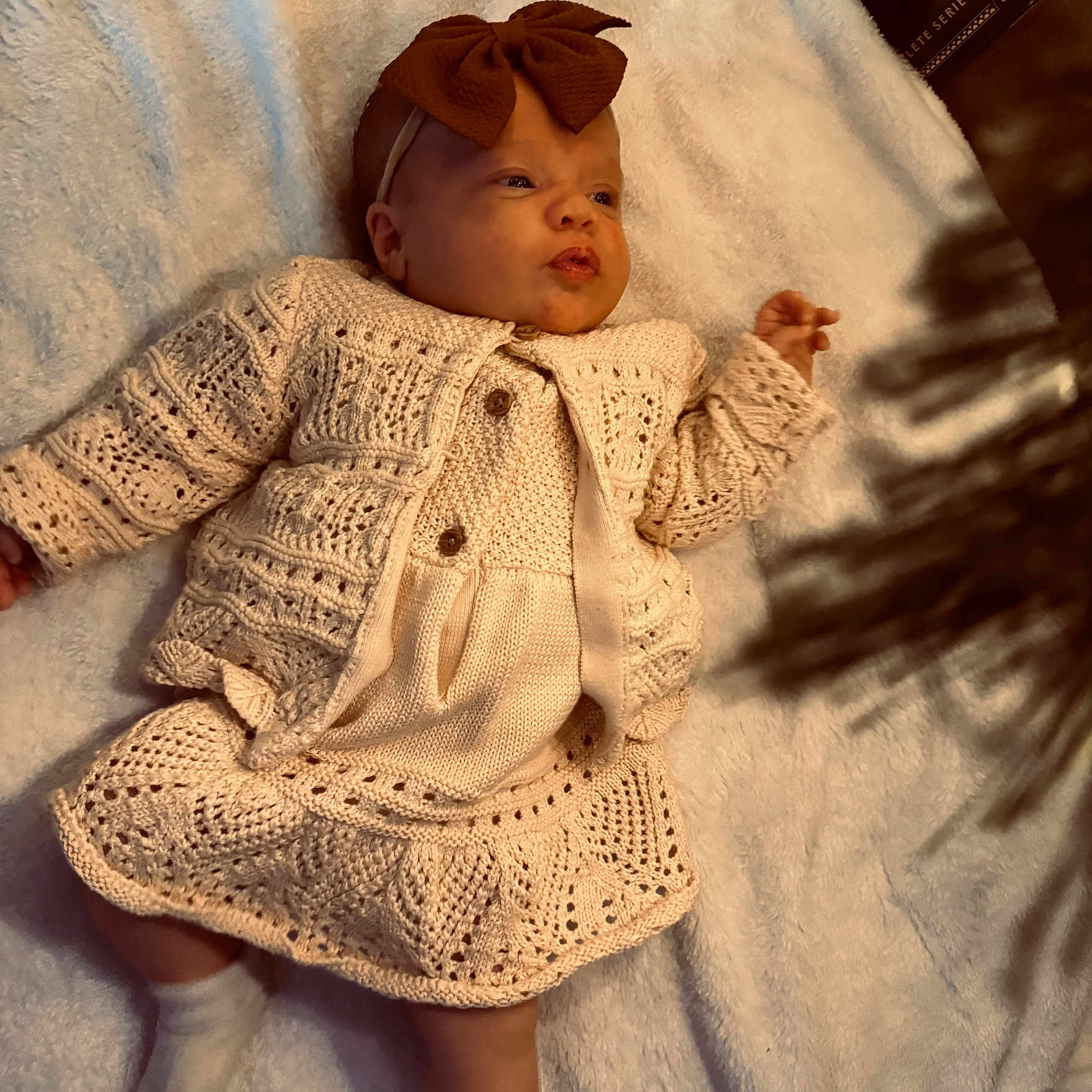 Tenley is registered to the contest to win money with this photo: baby, blanket, bow, child, cozy, cute, detail, expression, fashion, headband, indoors, infant, knitted_clothing, lying_down, newborn, portrait, shadow, skin, soft_texture, warm_lighting