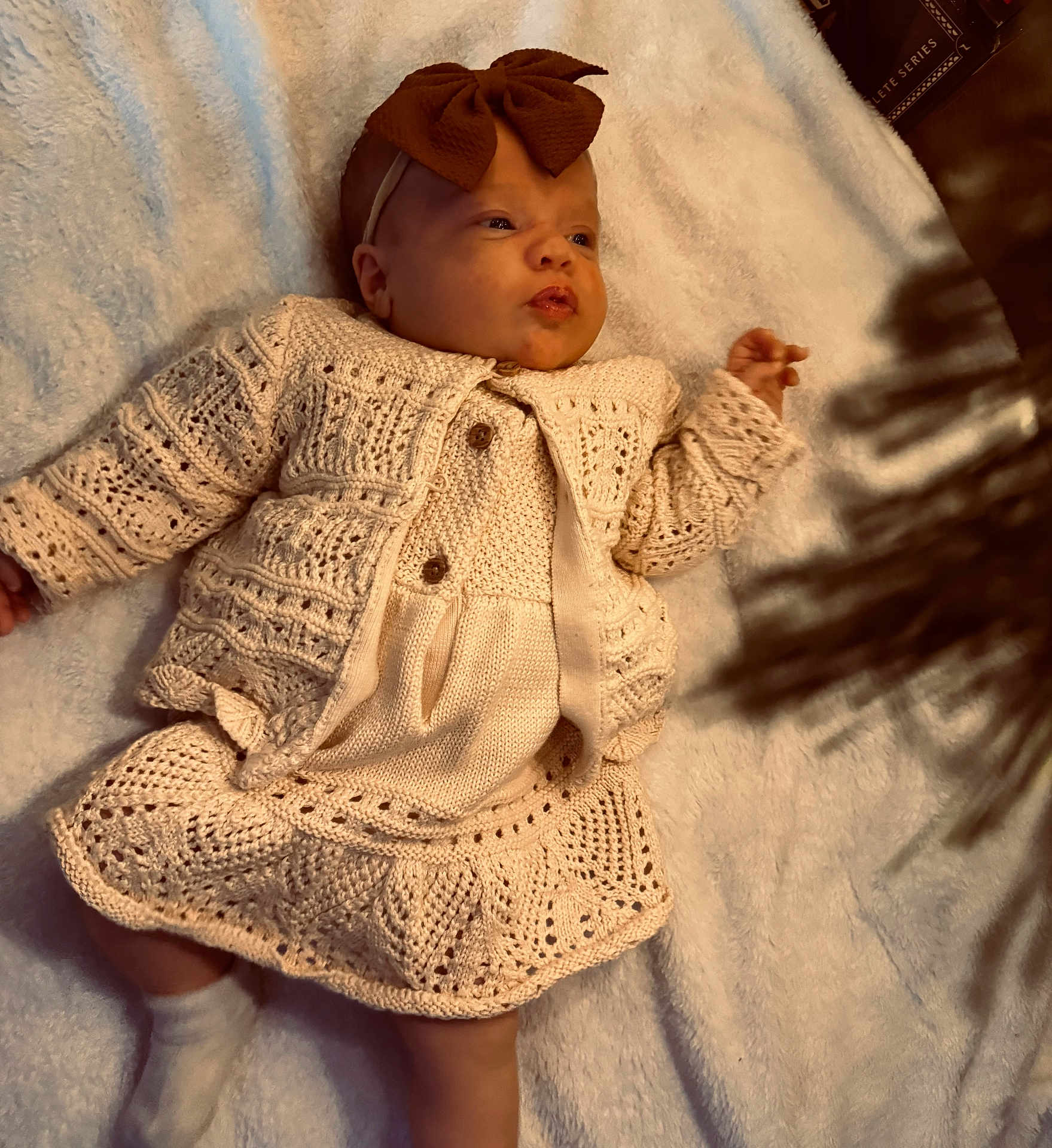 Tenley is registered to the contest to win money with this photo: baby, infant, knitted_clothing, headband, bow, blanket, soft_texture, shadow, lying_down, cute, warm_lighting, cozy, child, newborn, fashion, portrait, indoors, detail, expression, skin