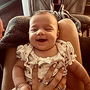 Tenley Kate is registered to the contest to win money with this photo: baby, smile, infant, hand, rings, clothing, person, lap, furniture, blanket, cozy, home, warm_light, happy, cute, skin, face, sitting, holding, indoor