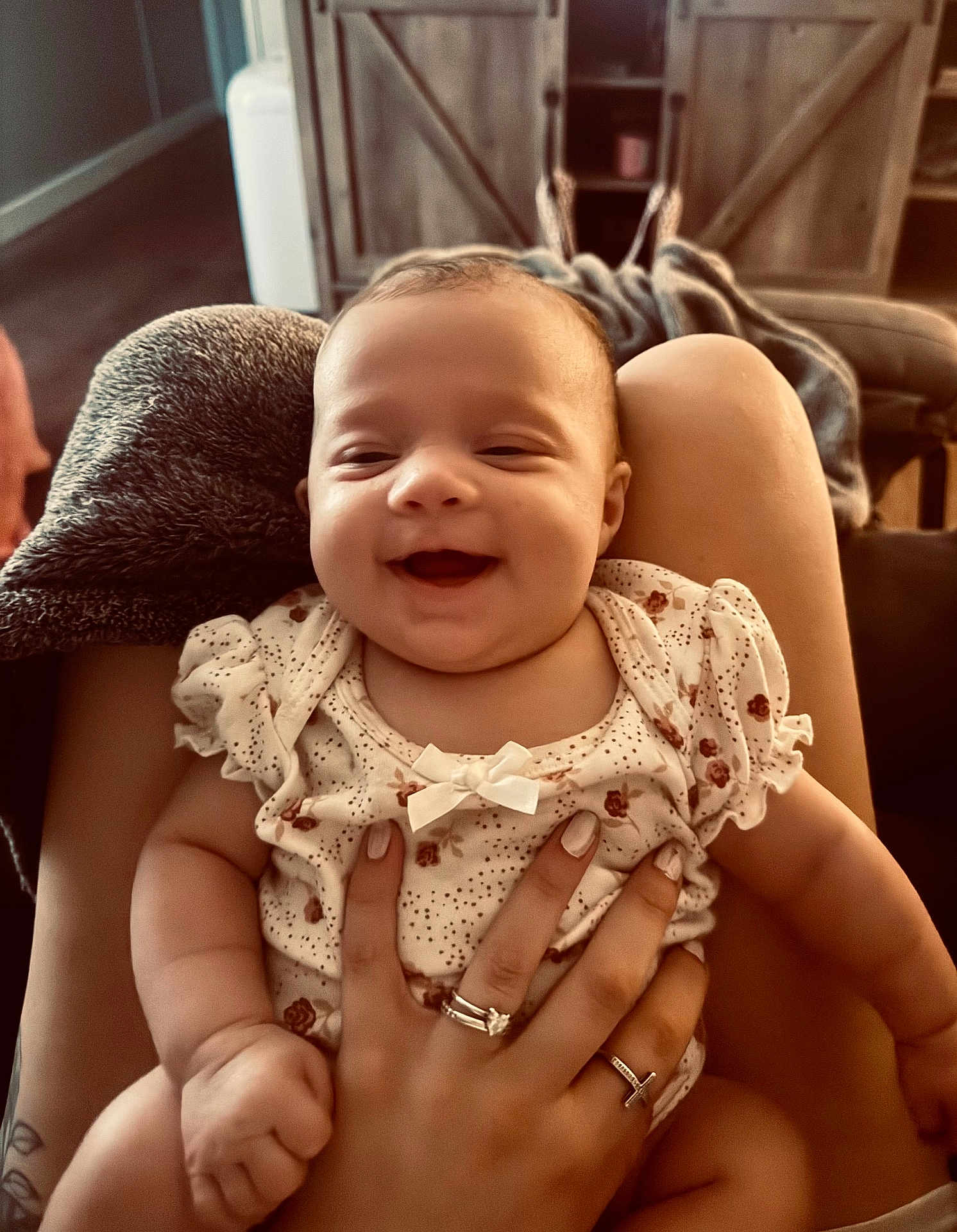 Tenley Kate is registered to the contest to win money with this photo: baby, smile, infant, hand, rings, clothing, person, lap, furniture, blanket, cozy, home, warm_light, happy, cute, skin, face, sitting, holding, indoor