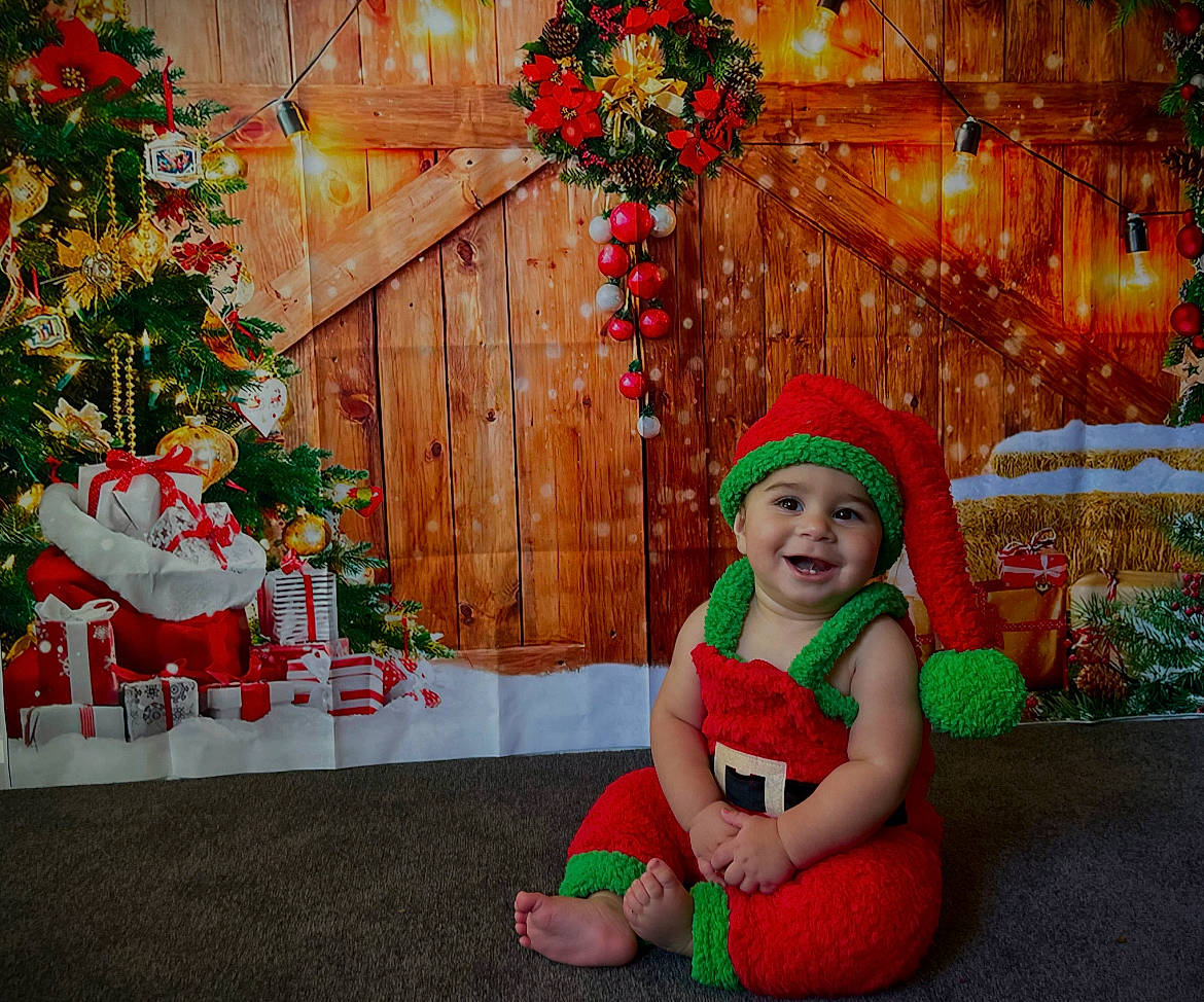 Jeziah is registered to the contest to win money with this photo: christmas, christmas_decoration, christmas_ornament, christmas_tree, decoration, event, grass, green, happy, hat, headwear, holiday, holiday_ornament, joy, lap, ornament, person, plant, red, smile