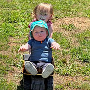 Sebastian is registered to the contest to win money with this photo: baby, blue_clothing, child, children, curly_hair, daylight, dump_truck, fun, grass, happy, hat, nature, outdoor, pink_clothing, play, sibling, smile, sunny, toddler, toy