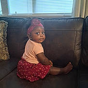 Sabrina is registered to the contest to win money with this photo: toddler, child, girl, sitting, couch, leather, head_wrap, pink_shirt, red_skirt, indoor, window, blinds, pillow, curious, face, person, furniture, home, portrait, cute