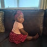 toddler, child, girl, sitting, couch, leather, head_wrap, pink_shirt, red_skirt, indoor, window, blinds, pillow, curious, face, person, furniture, home, portrait, cute