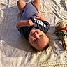 baby, child, smiling, lying_down, blanket, soft_toy, onesie, indoor, cute, infant, face, happy, skin, hand, foot, head, person, portrait, cozy, toddler