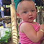 toddler, child, baby, headband, green_bow, pink_tank_top, colorful_skirt, tattoo, arm, wooden_post, wire_fence, outdoor, daylight, person, cute, blue_eyes, portrait, holding, clothing, nature