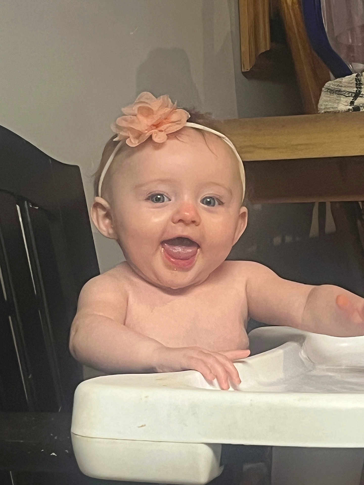 Maizy joined the competition — help win amazing prizes! baby, child, high_chair, smiling, happy, headband, flower, indoor, person, face, mouth_open, skin, arm, table, furniture, seat, cute, infant, expression, tongue