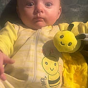 Maizy joined the competition — help win amazing prizes! baby, child, yellow, onesie, bee, plush_toy, blanket, face, person, infant, cute, indoors, soft_texture, clothing, smile, young, expression, hand, portrait, cozy